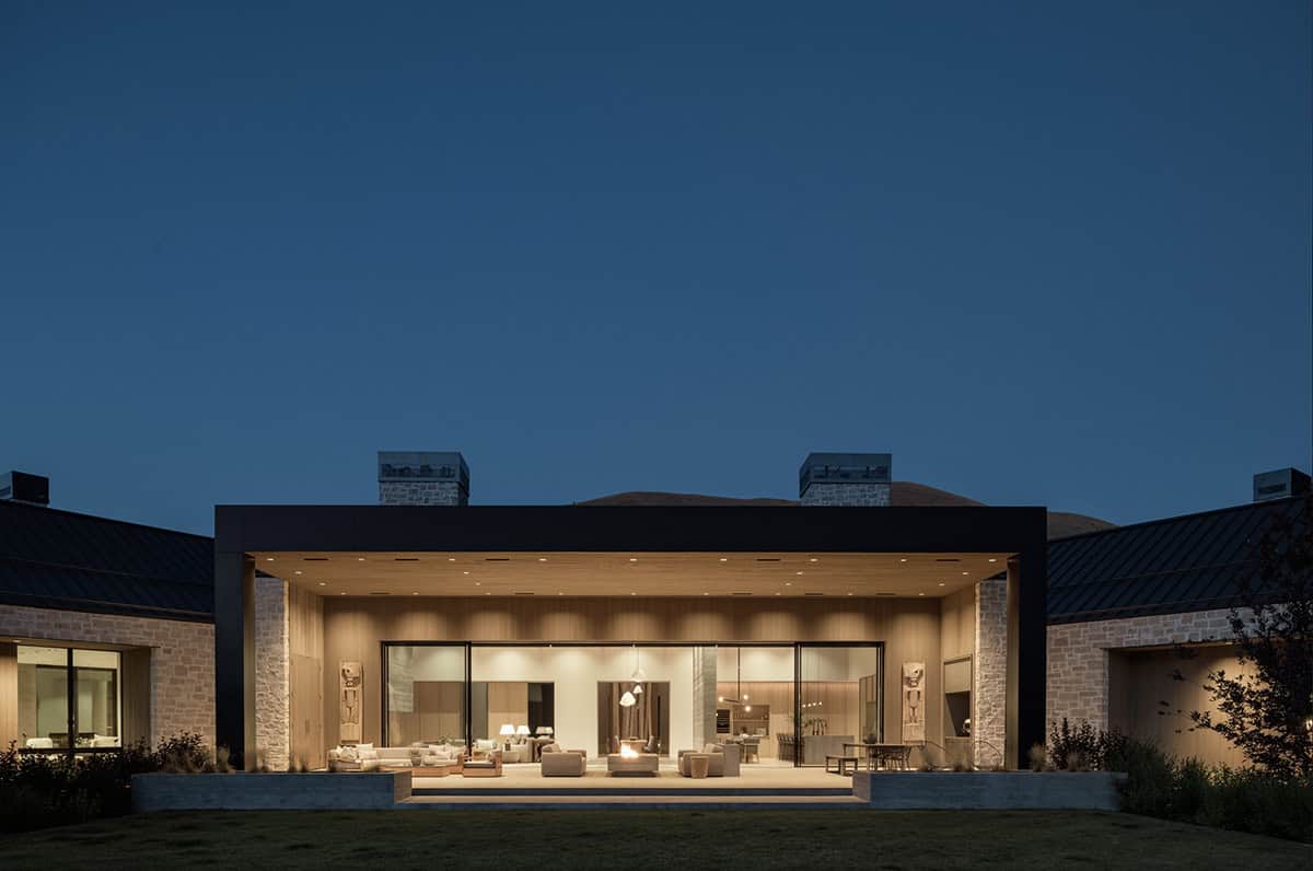 Twilight exterior of the home's central pavilion with glowing interior and fire feature