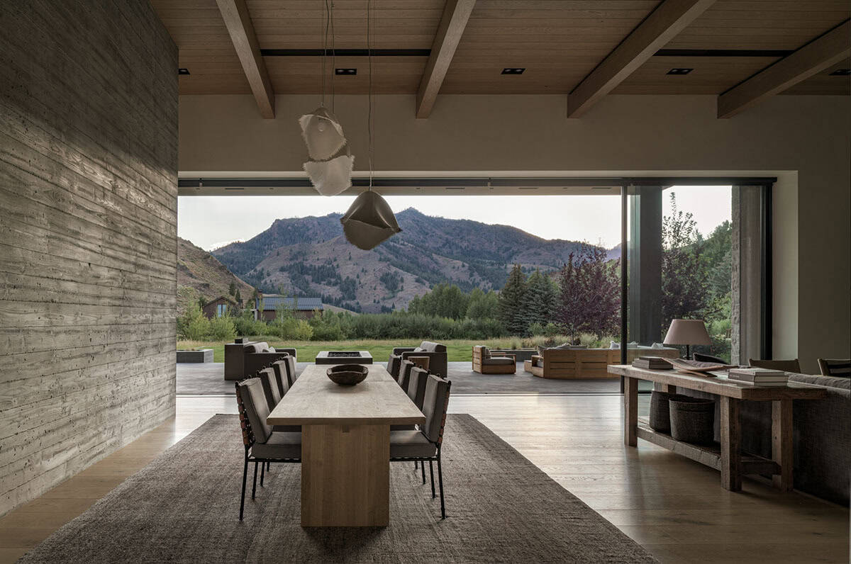 Dining area opening to a covered patio with sweeping mountain backdrop at dusk