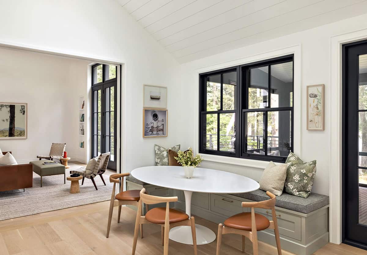 Breakfast nook with oval white table, leather chairs, and built-in bench seating by black-framed windows