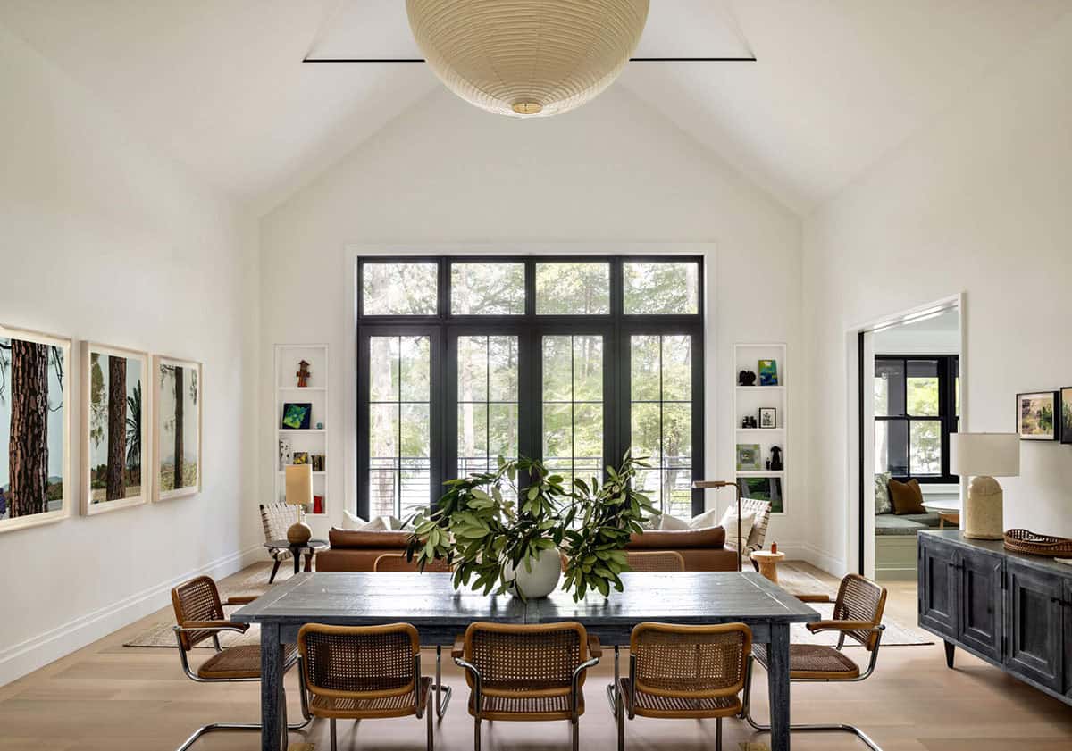 Dining room with vaulted ceiling, paper lantern pendant, dark wood table, and floor-to-ceiling black windows