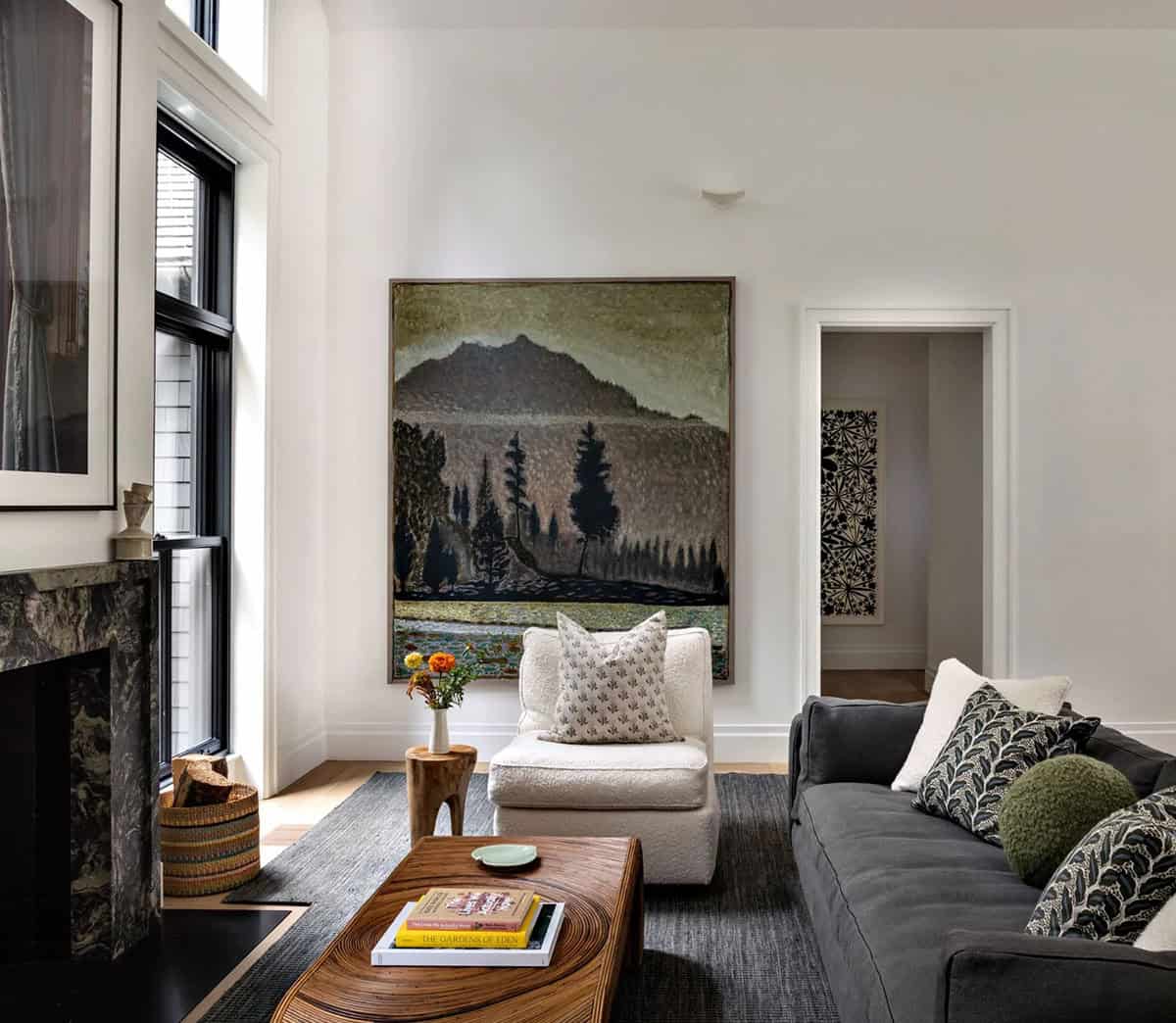 Cozy living room corner with marble fireplace, cream armchair, and large framed landscape painting