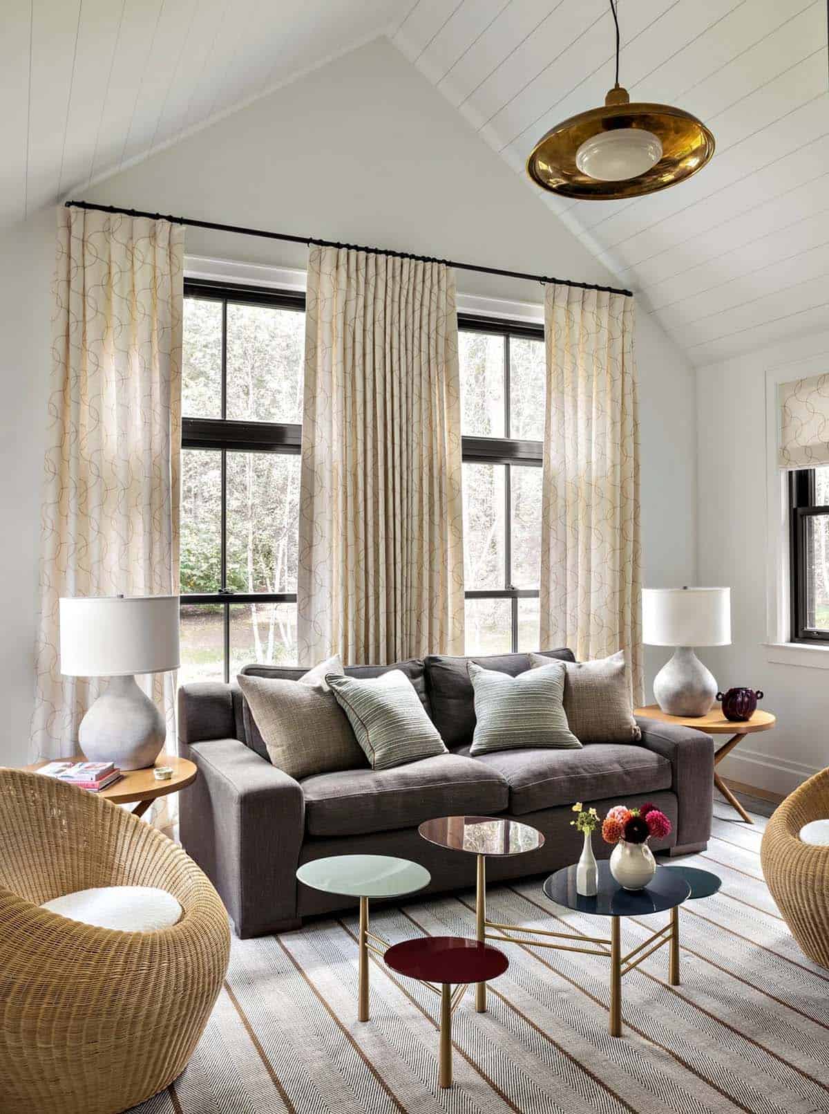 Sitting room with patterned curtains, wicker chairs, gray sofa, and brass pendant light