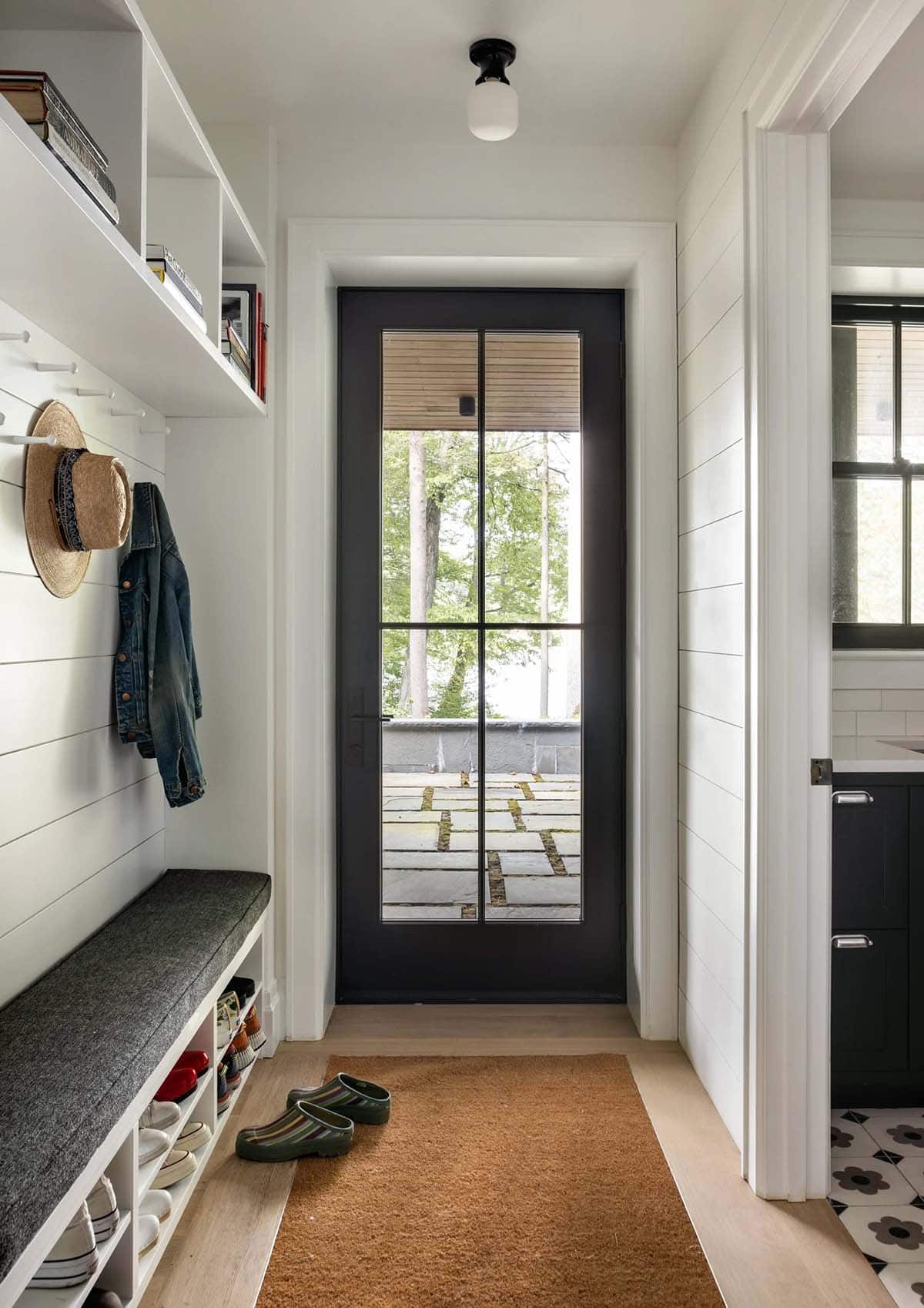 Mudroom hallway with shoe storage bench, hooks, and dark French door leading outside