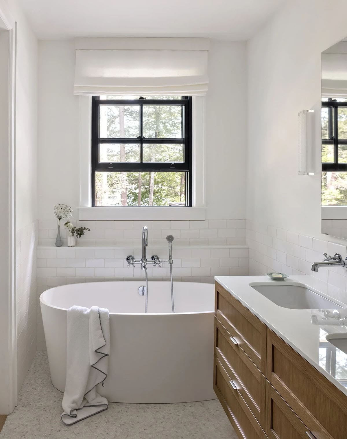 Bathroom with freestanding white tub, subway tile, and wood vanity with double sinks