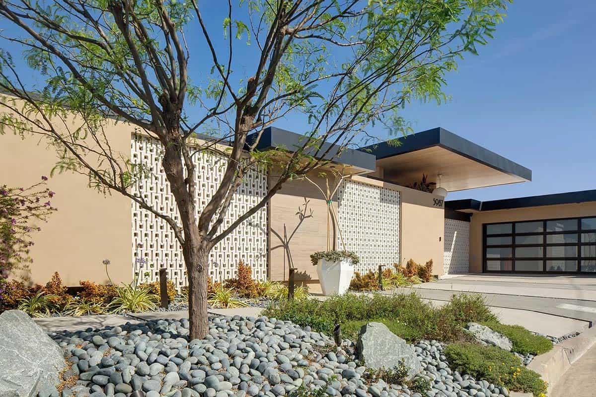 Front exterior with feathery tree, river rock landscaping, and patterned breeze block facade panels