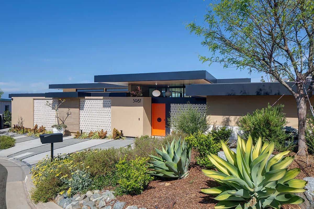 Full street-facing facade showing flat roof, orange entry door, drought-tolerant landscaping with agave and native shrubs