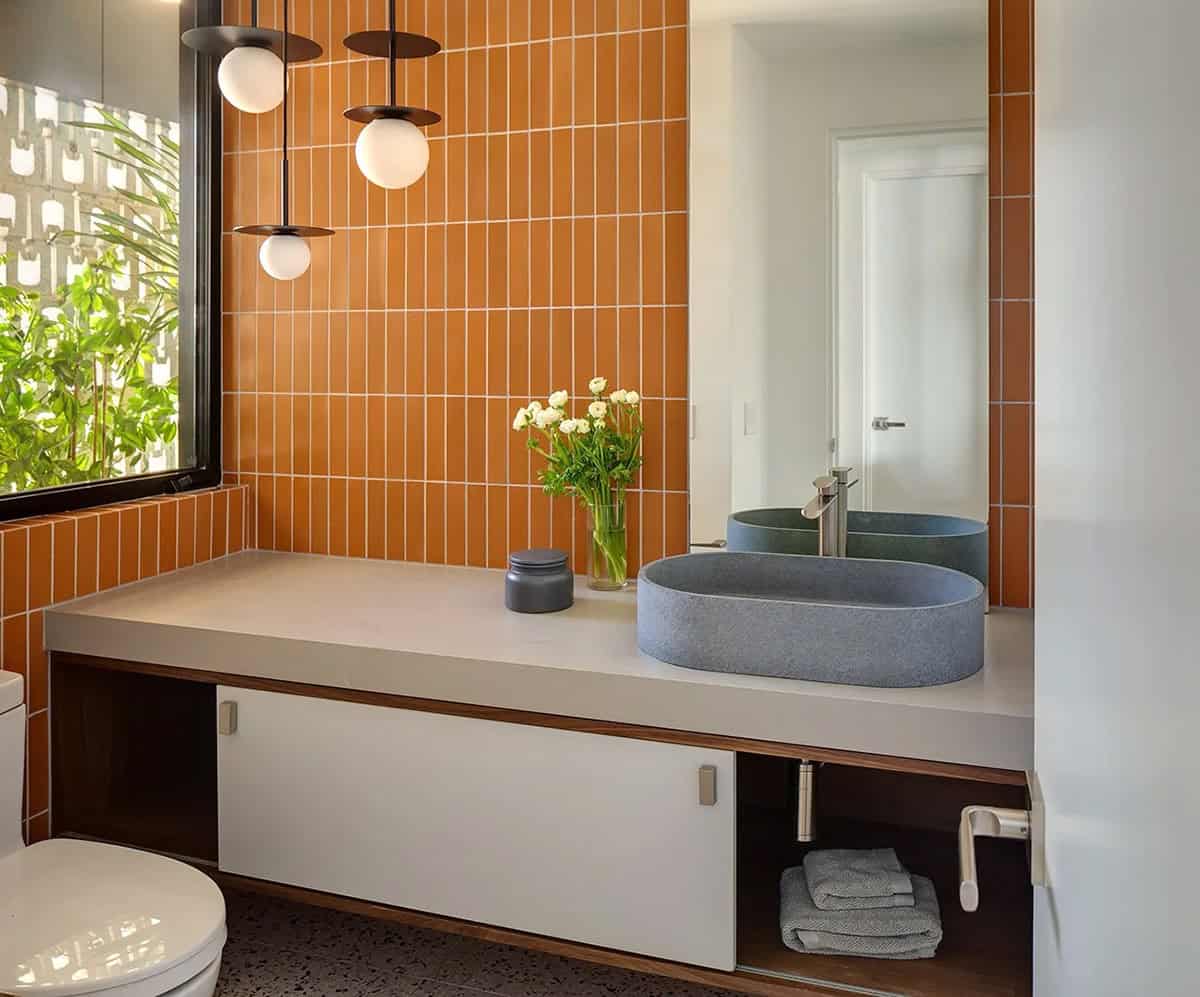 Guest bathroom with terracotta vertical tile, oval stone vessel sink, floating vanity, and globe pendant cluster