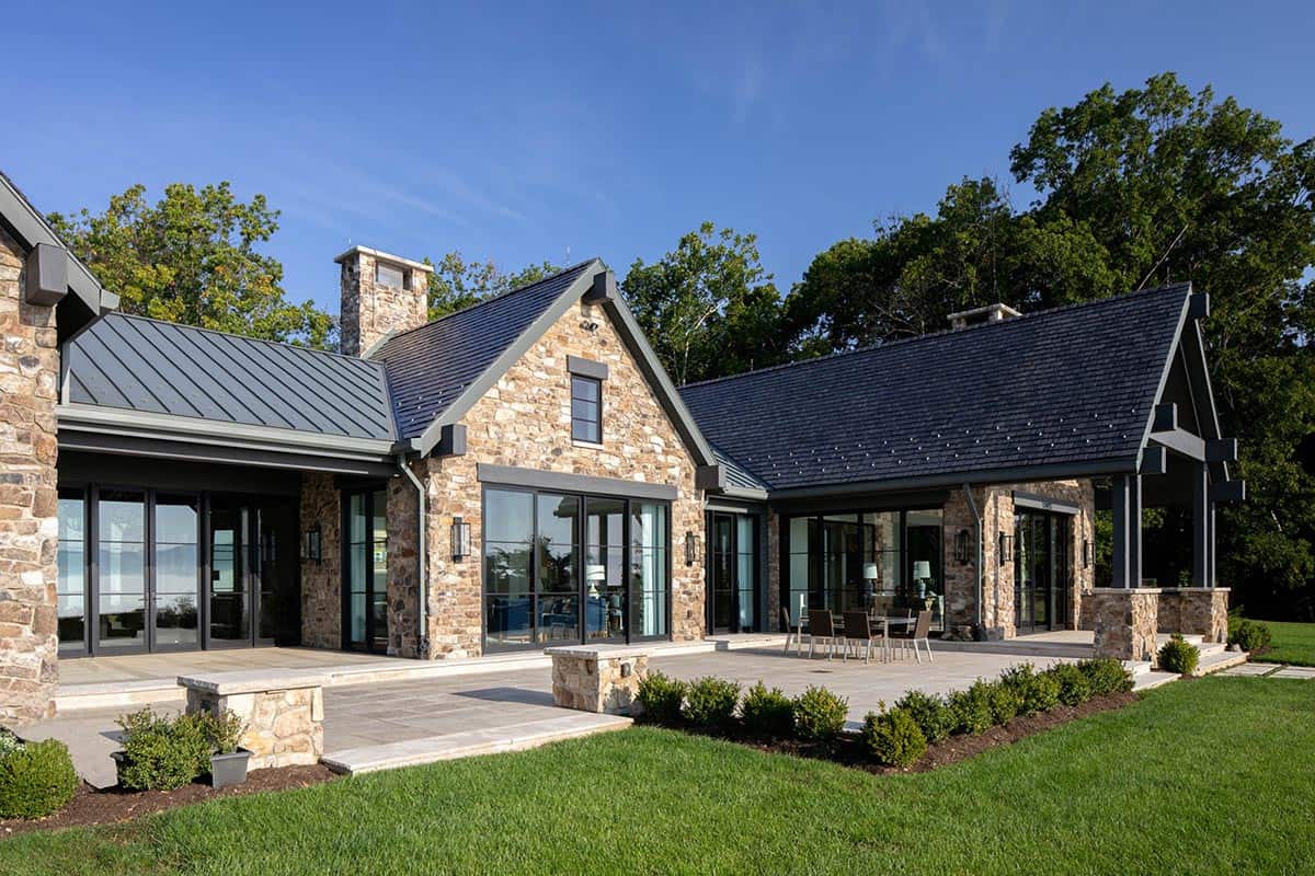 Stone exterior with multiple gables, folding glass doors, and stone patio set for outdoor dining