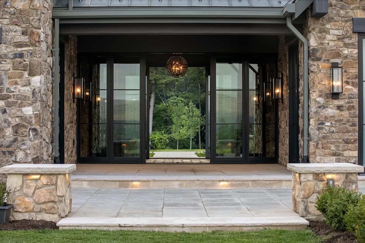 Folding glass entry doors framed in stone with globe pendant light revealing mountain view beyond