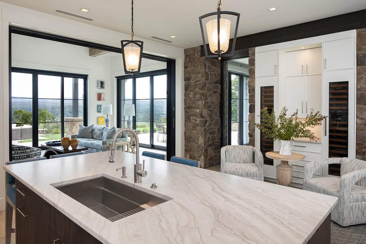 Kitchen island with marble countertop and undermount sink opening to living room with mountain views beyond