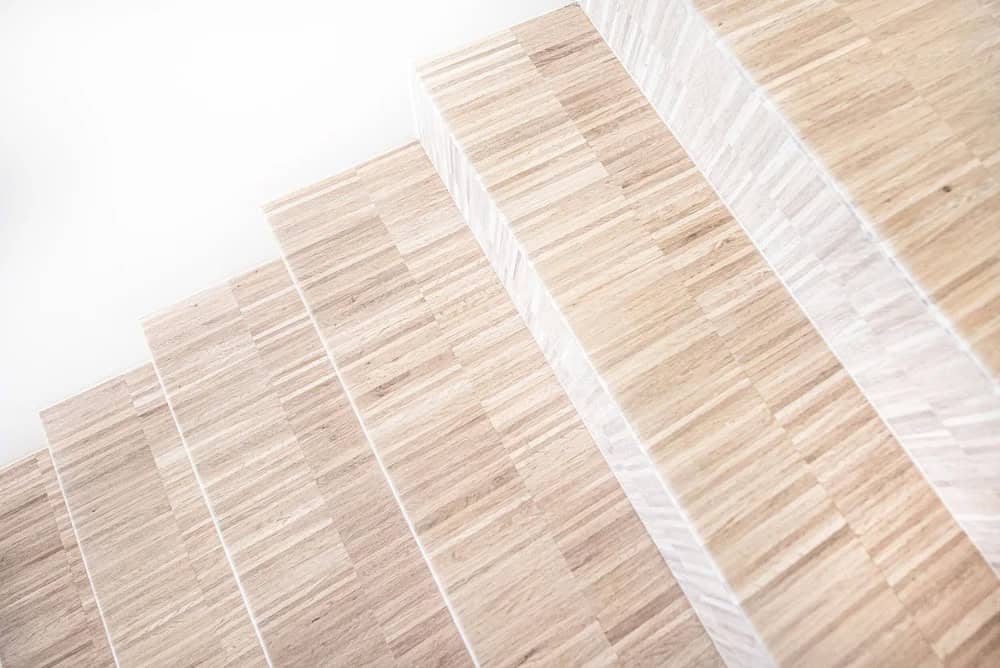 Close-up of light wood stair treads with subtle linear grain texture against a white wall