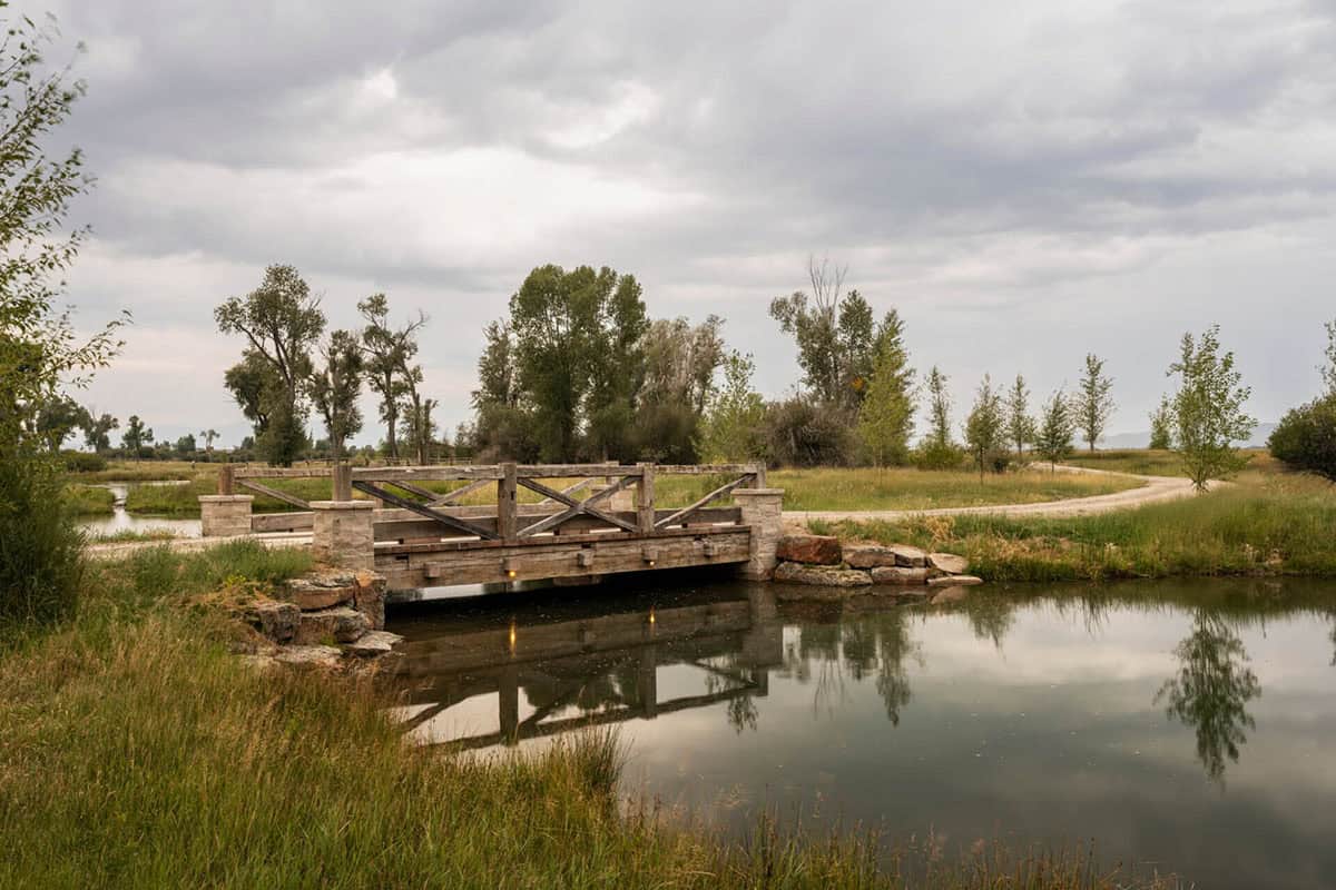 Rustic timber and stone bridge over a pond on a Montana ranch property