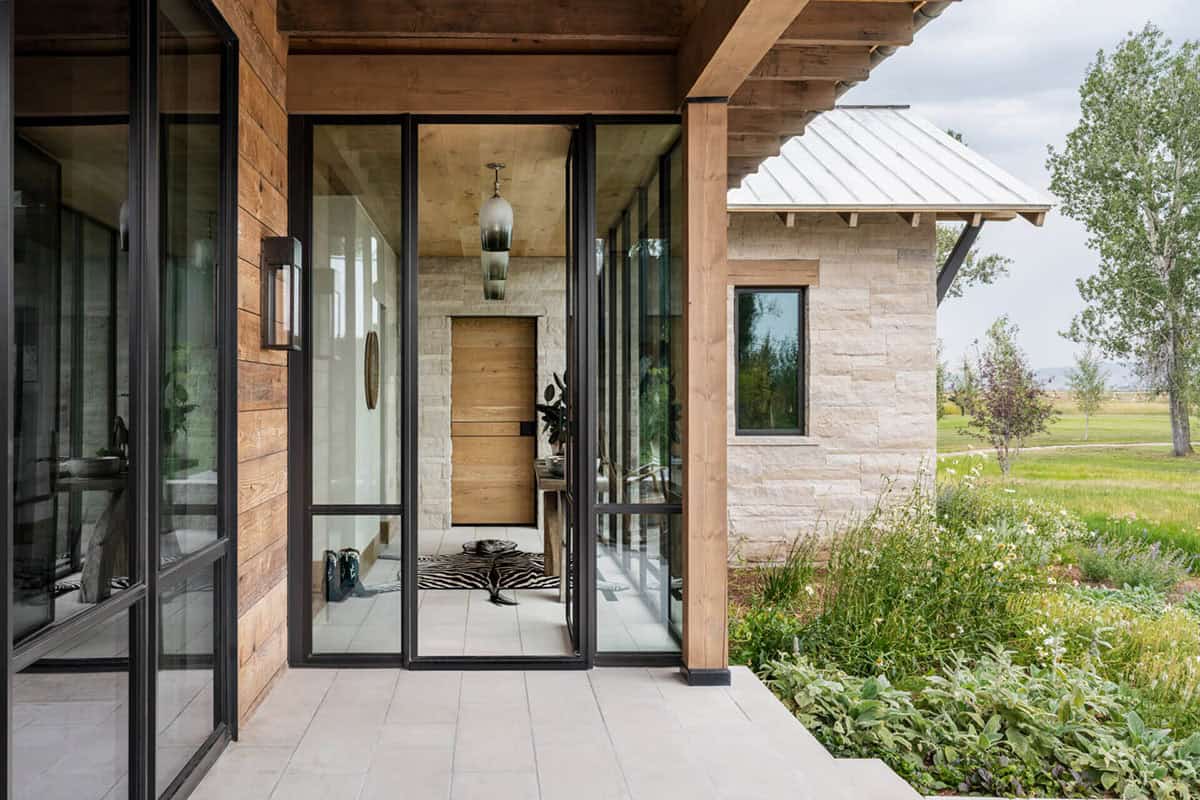 Glass-walled entry vestibule with wood pivot door, pendant light, and zebra rug