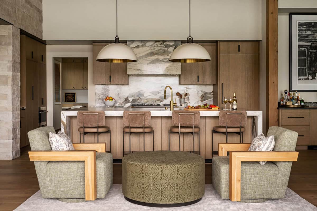 Kitchen sitting area with green swivel chairs and round ottoman facing a marble island