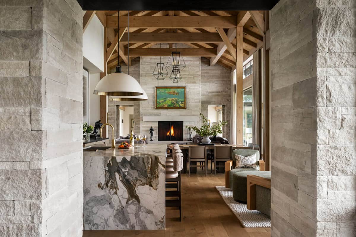 View through stone archway into open-plan living, dining, and kitchen with fireplace beyond