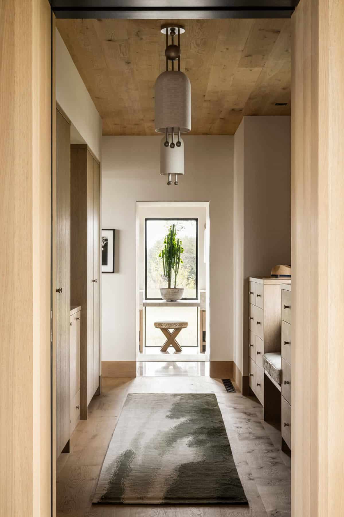 Light-filled hallway with oak cabinetry, abstract runner rug, and window framing a potted cactus