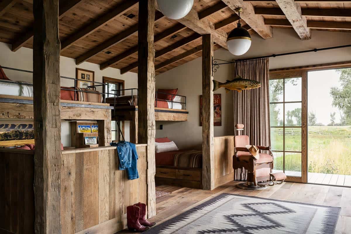 Rustic bunk room with reclaimed timber beams, built-in bunks, Navajo rug, and vintage barber chair