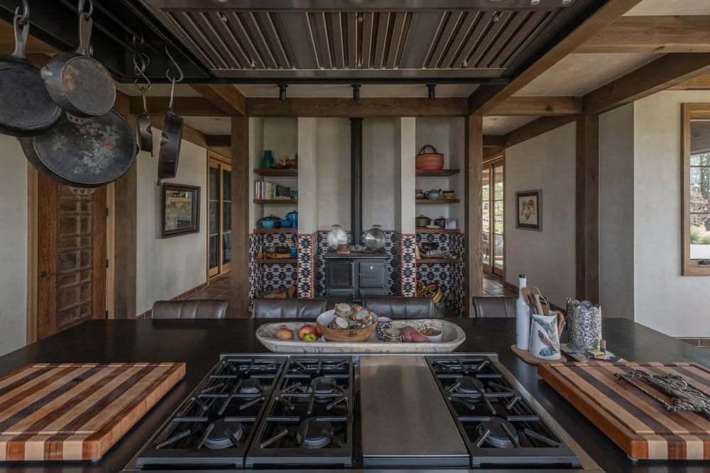 Kitchen island with built-in gas cooktop and wood-trimmed pot rack overhead