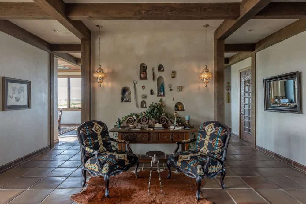 Sitting nook with carved console table, decorative wall niches, and patterned armchairs