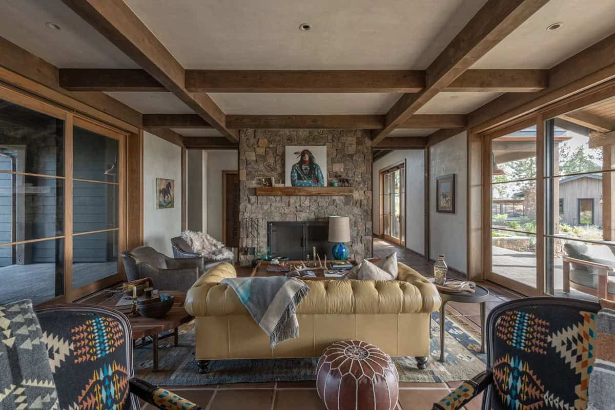 Living room with stone fireplace, beamed ceiling, and tufted leather sofa