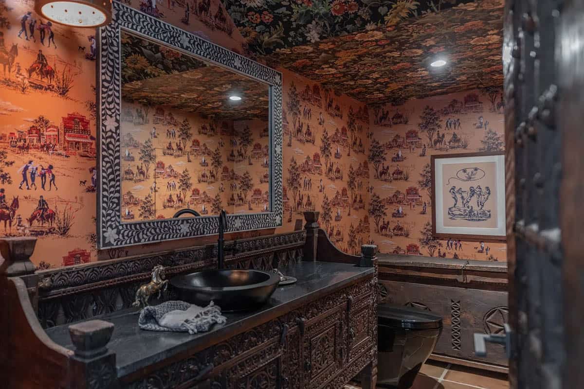 Powder room with western-themed wallpaper and carved wood vanity