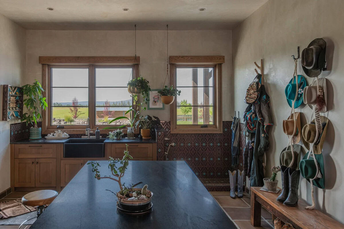 Kitchen with farmhouse sink, tiled backsplash, and wall of hanging cowboy hats