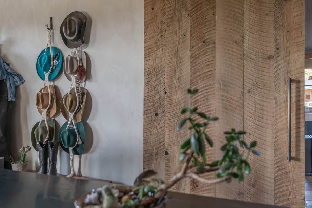 Close-up of cowboy hats hung on wall beside reclaimed wood barn door