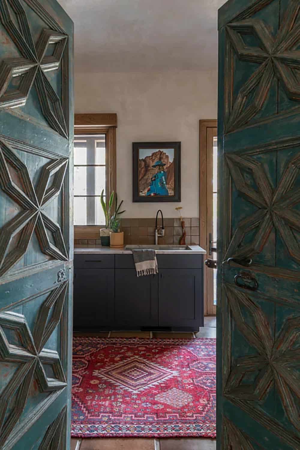 Carved wooden doors opening to kitchenette with patterned rug