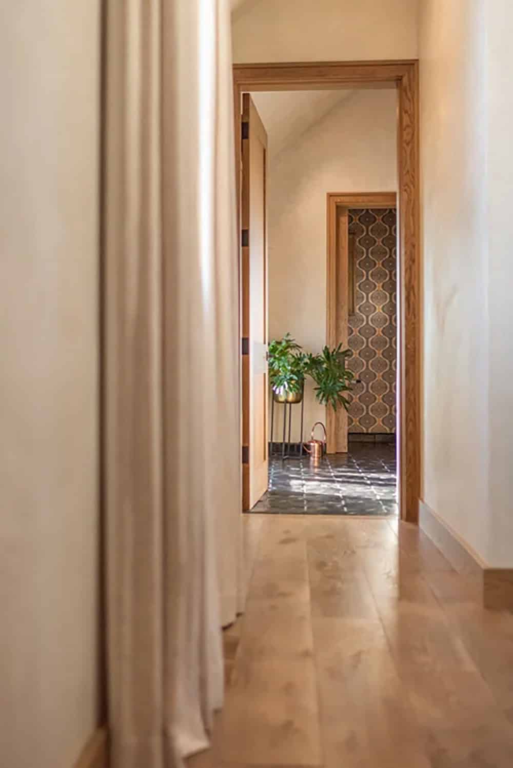 Hallway leading to bathroom with patterned tile floor and houseplants