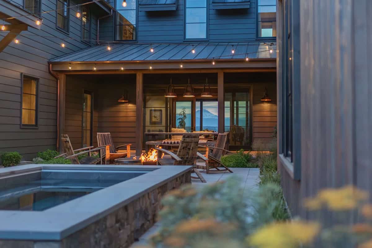 Backyard patio with fire pit, hot tub, and string lights at dusk