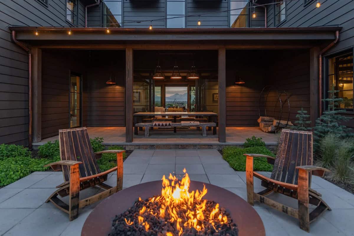 Covered patio with fire pit and barrel chairs overlooking mountain view at dusk