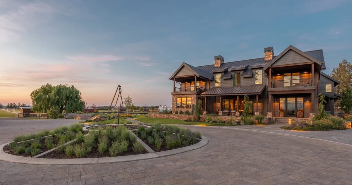 Aerial dusk view of dark wood ranch house with circular driveway garden
