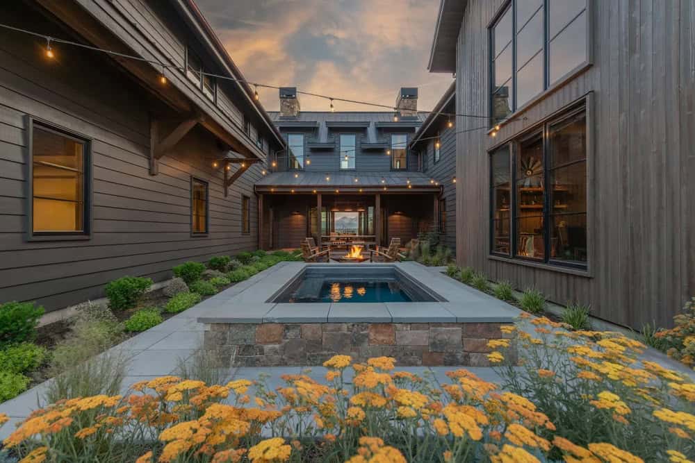 Courtyard with sunken hot tub, fire pit, and string lights between wings of house