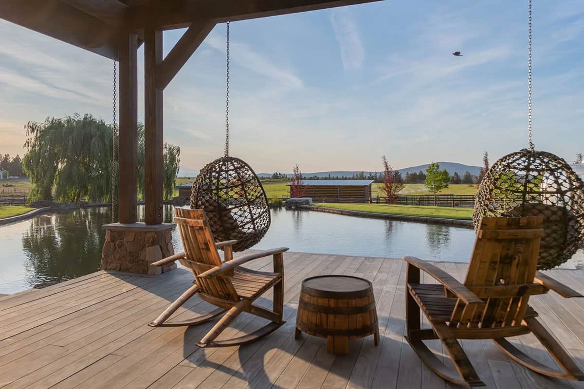 Deck with hanging chairs and rocking chairs overlooking pond