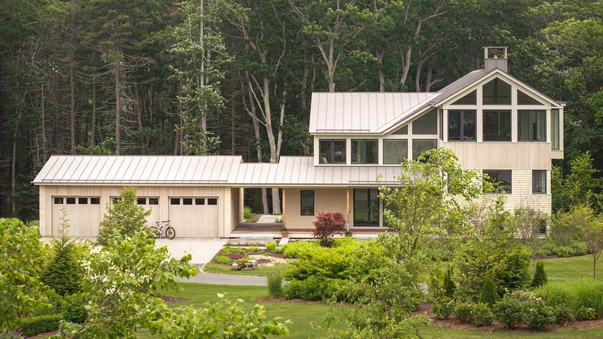 Front exterior of modern Maine home with three-car garage, metal roof, and large gable windows
