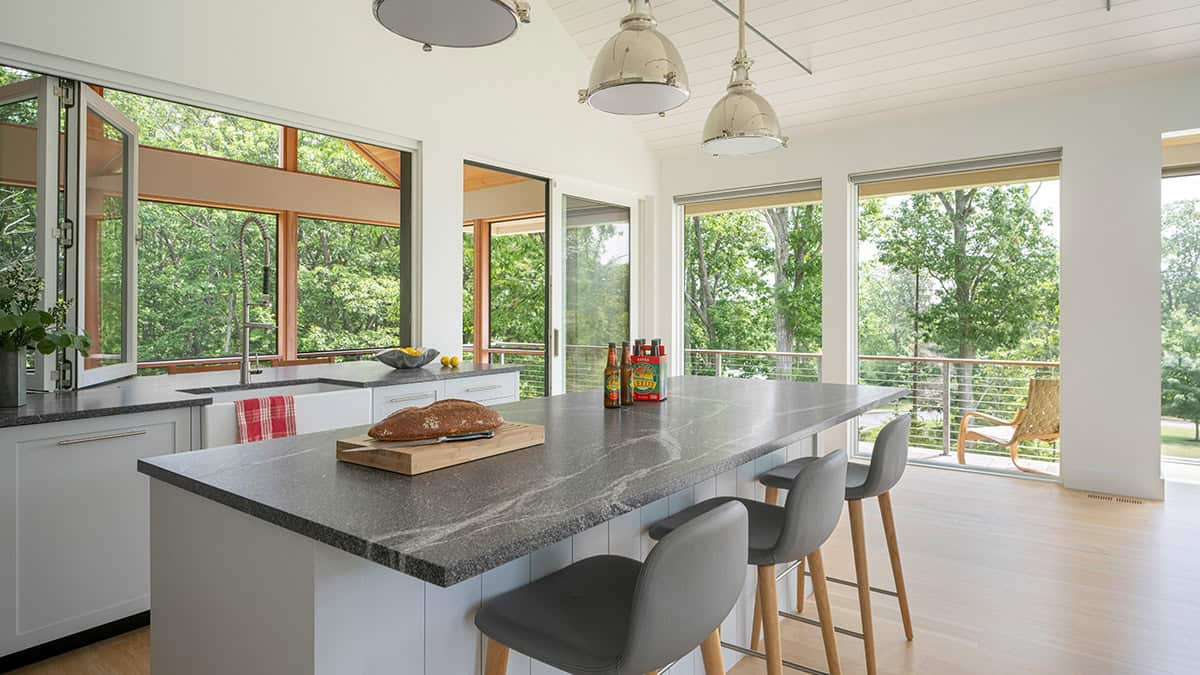 Kitchen island with soapstone countertop and bi-folding window open to screened porch and treetops