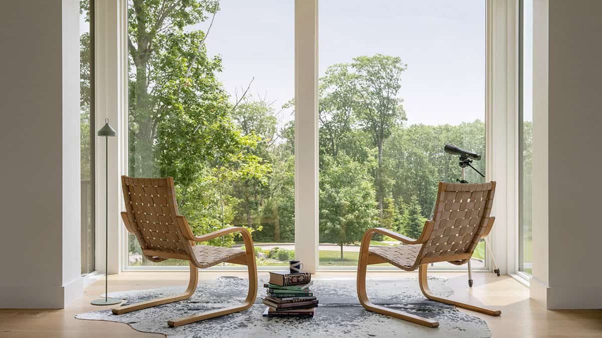 Pair of Aalto lounge chairs facing floor-to-ceiling windows overlooking wooded landscape