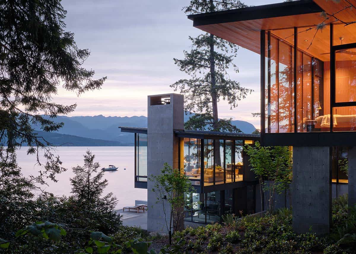 Multi-level glass pavilion with cedar soffits and mountain lake views at sunset