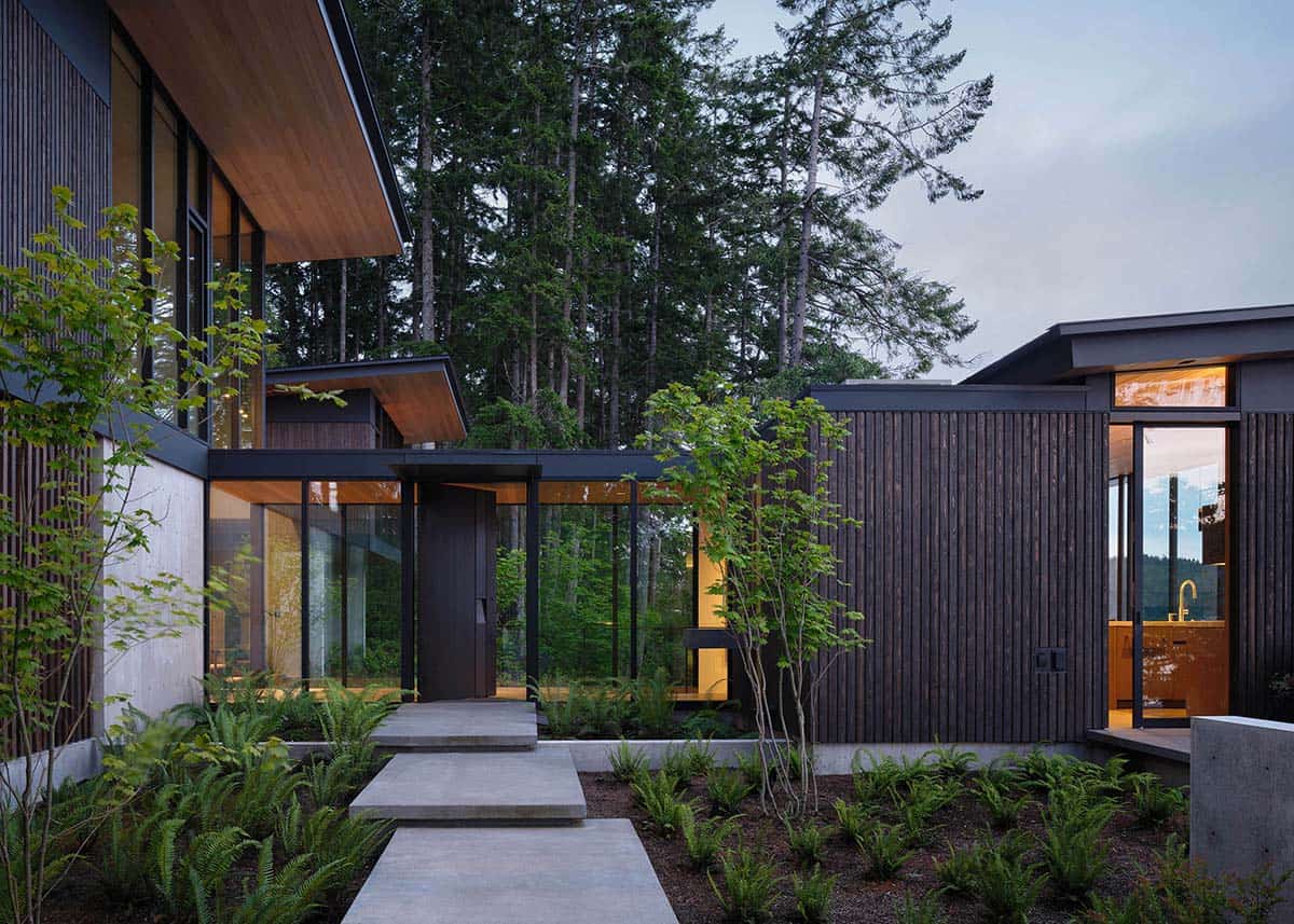Dark wood-slat entry courtyard with fern landscaping and concrete stepping path