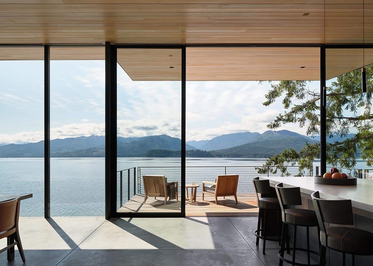 Kitchen interior opening to a cantilevered teak deck with mountain and lake views through floor-to-ceiling glass