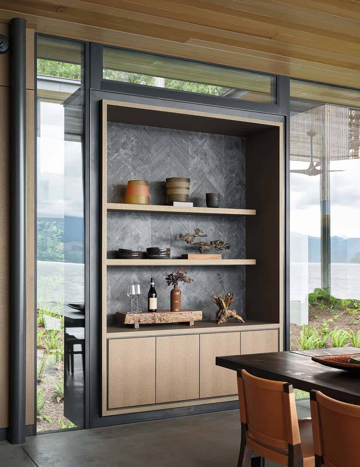 Built-in display shelving with herringbone slate tile backing beside dining area