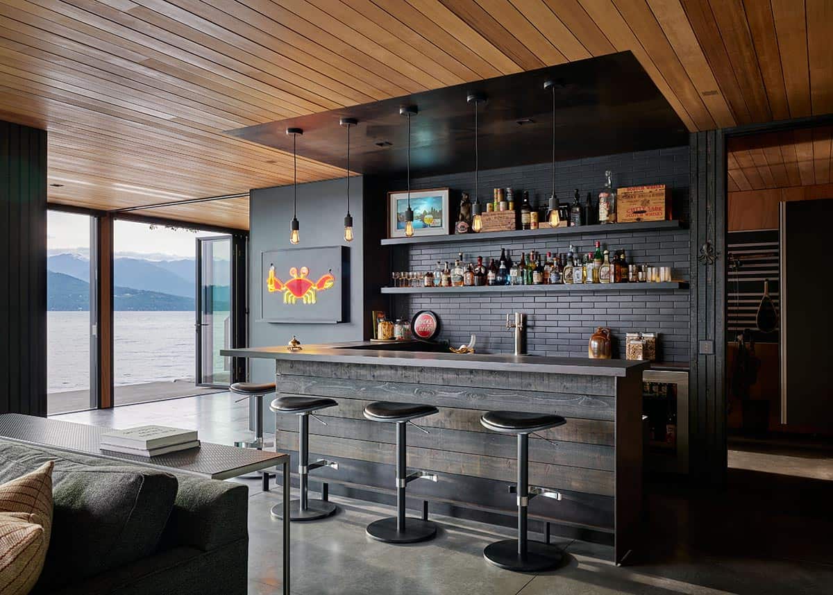 Rustic wood bar with metal stools, Edison bulb pendants, and open water views