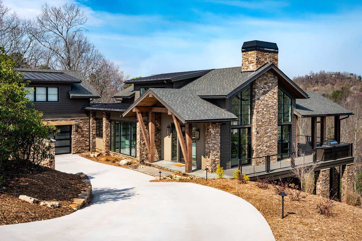 Mountain contemporary home exterior with stone facade, timber frame entry, and dark roof