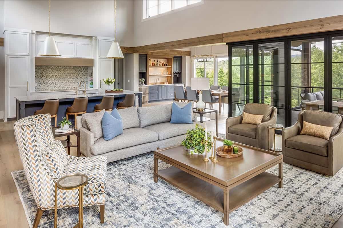 Open-plan living and kitchen area with exposed wood beams, blue island, and accordion doors to deck