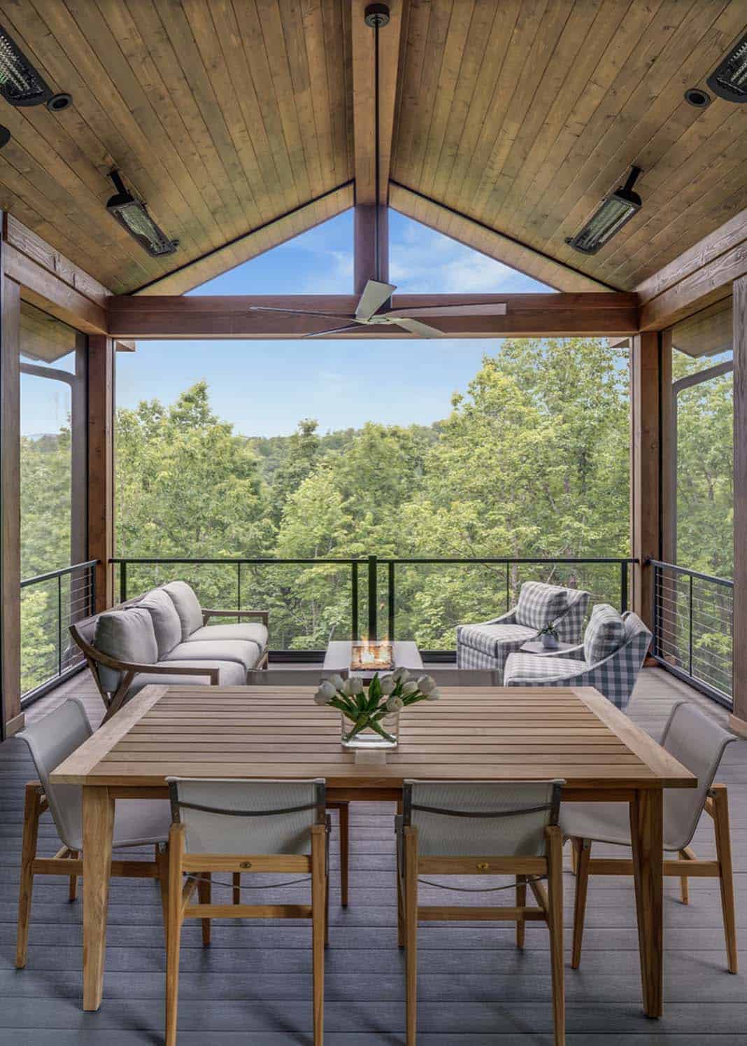 Covered outdoor deck with wood ceiling, teak dining table, and open views of forested mountains