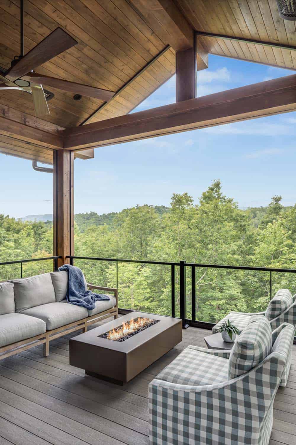 Screened porch with fire pit coffee table, plaid armchairs, and sweeping tree canopy views