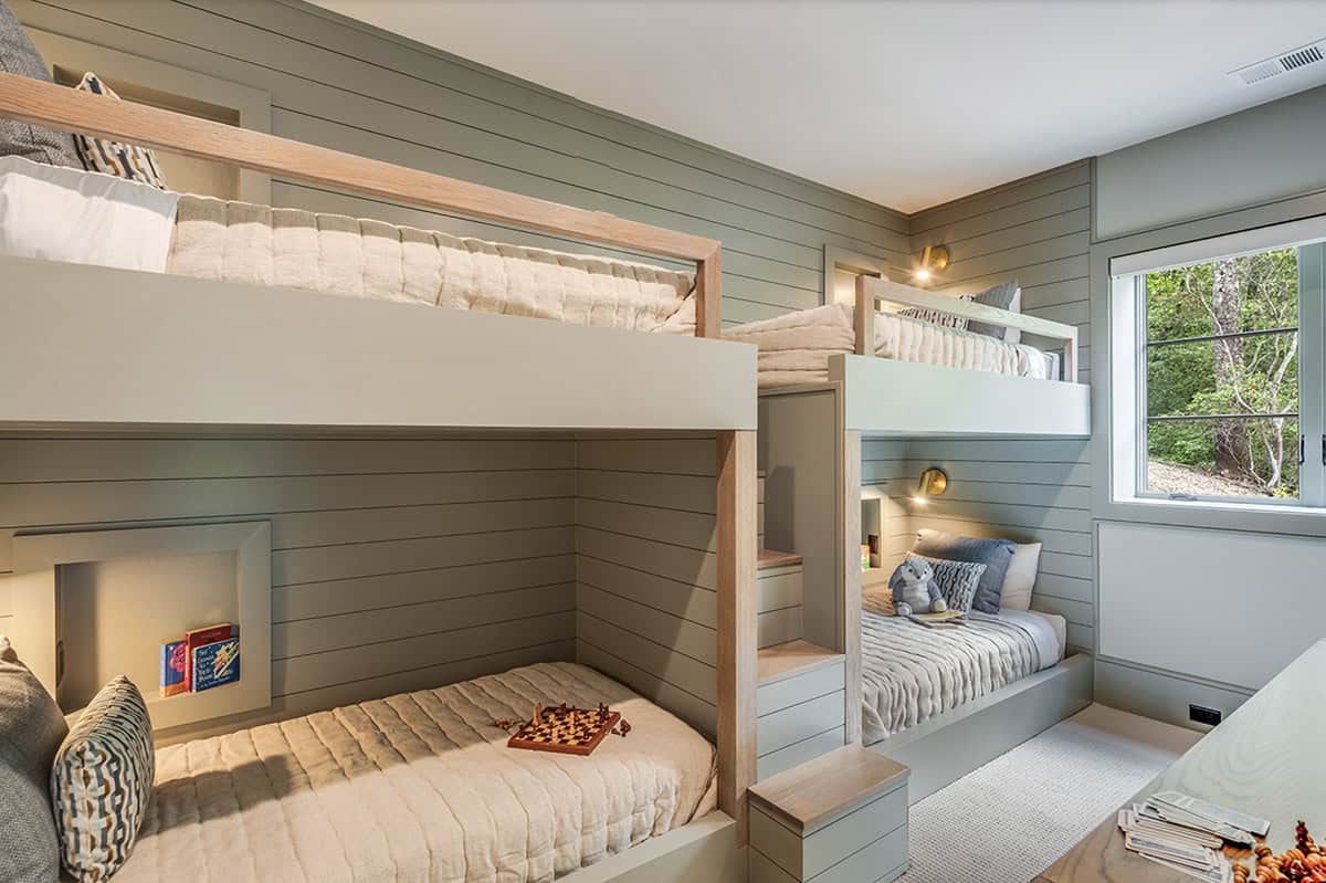 Kids bunk room with four built-in bunks, shiplap walls, reading nooks, and wood stair access