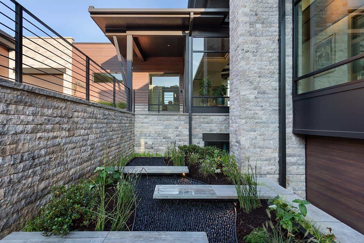 Entry courtyard with floating stone steps over black pebble garden bed