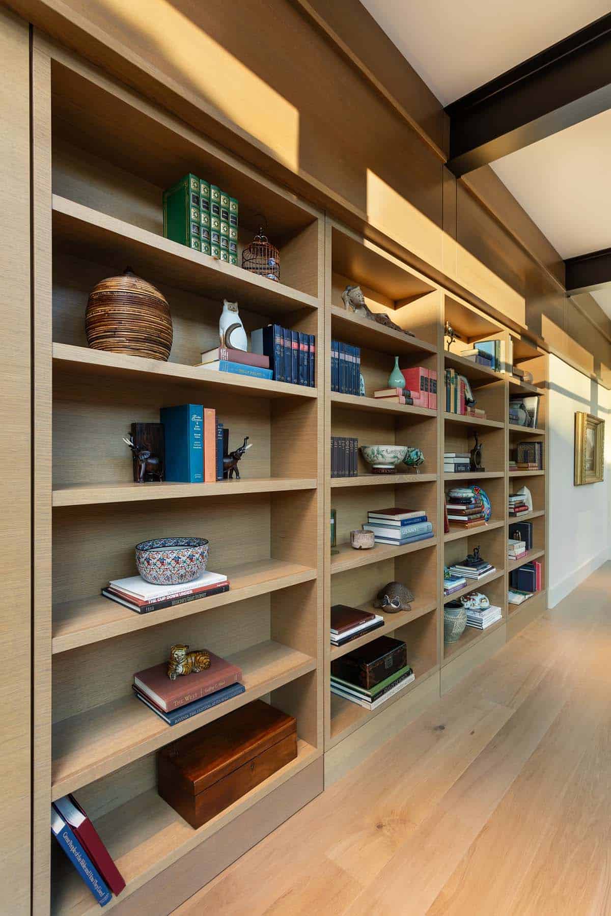 Floor-to-ceiling built-in oak bookshelves with curated books and decorative objects
