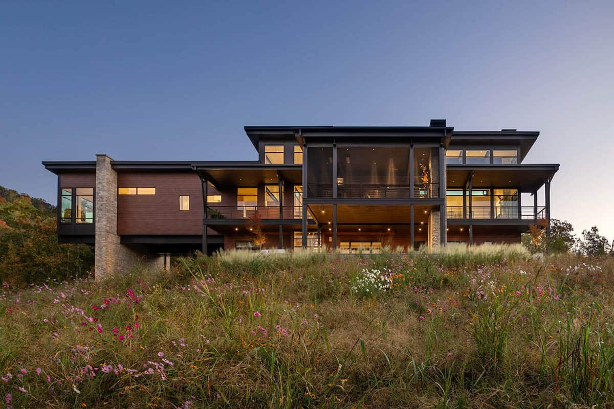 Illuminated rear elevation with screened porch and open decks at dusk
